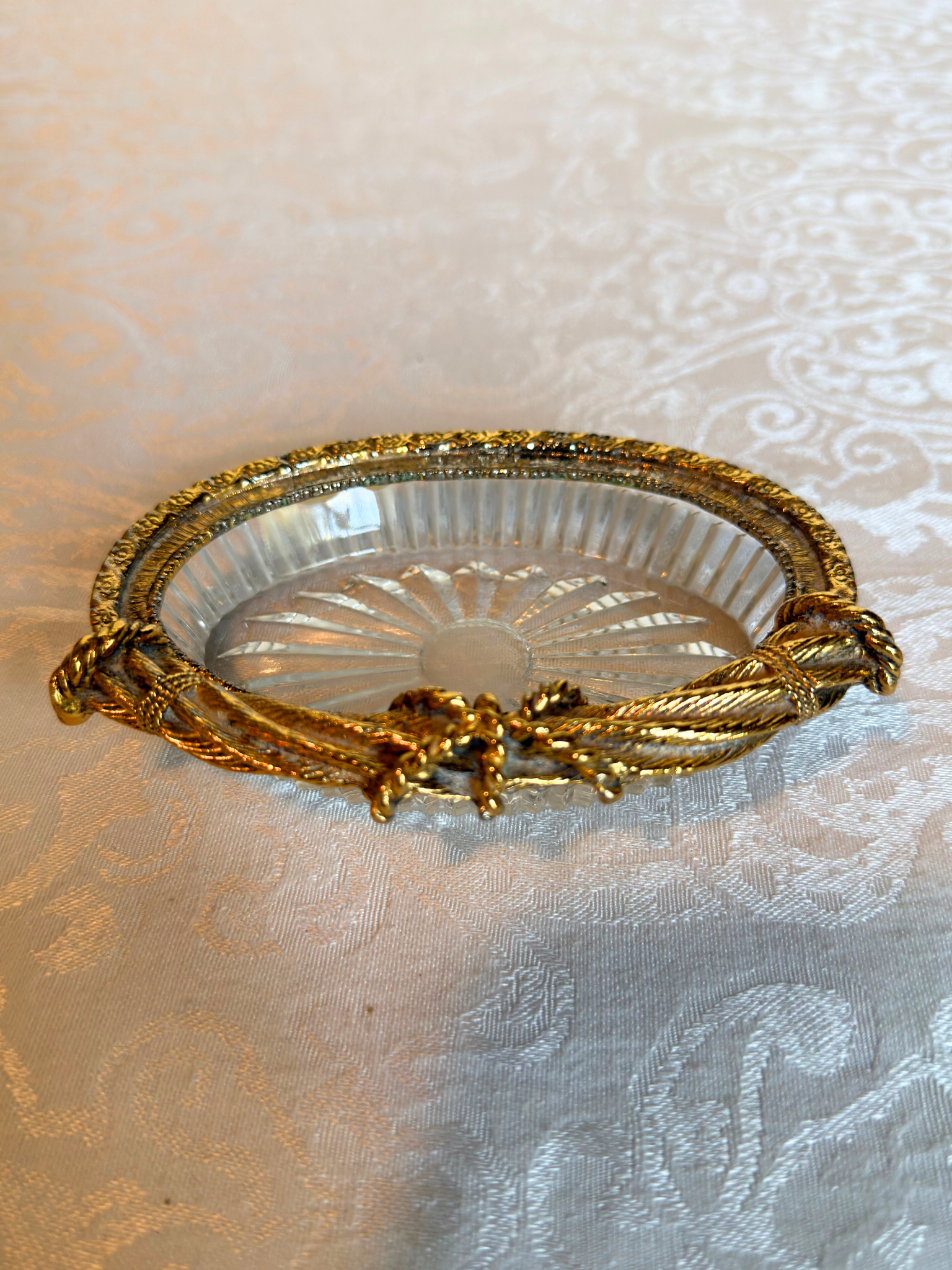 Decorative glass dish with gold rim on a textured white background