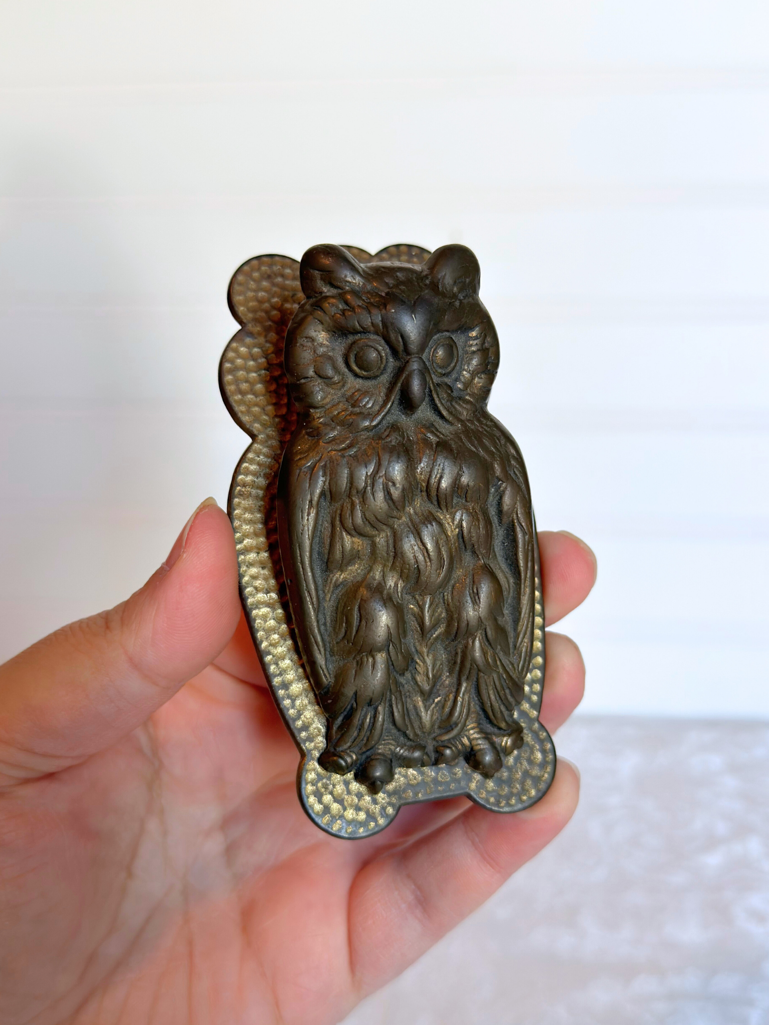 owl hand clip held in a hand against a white background