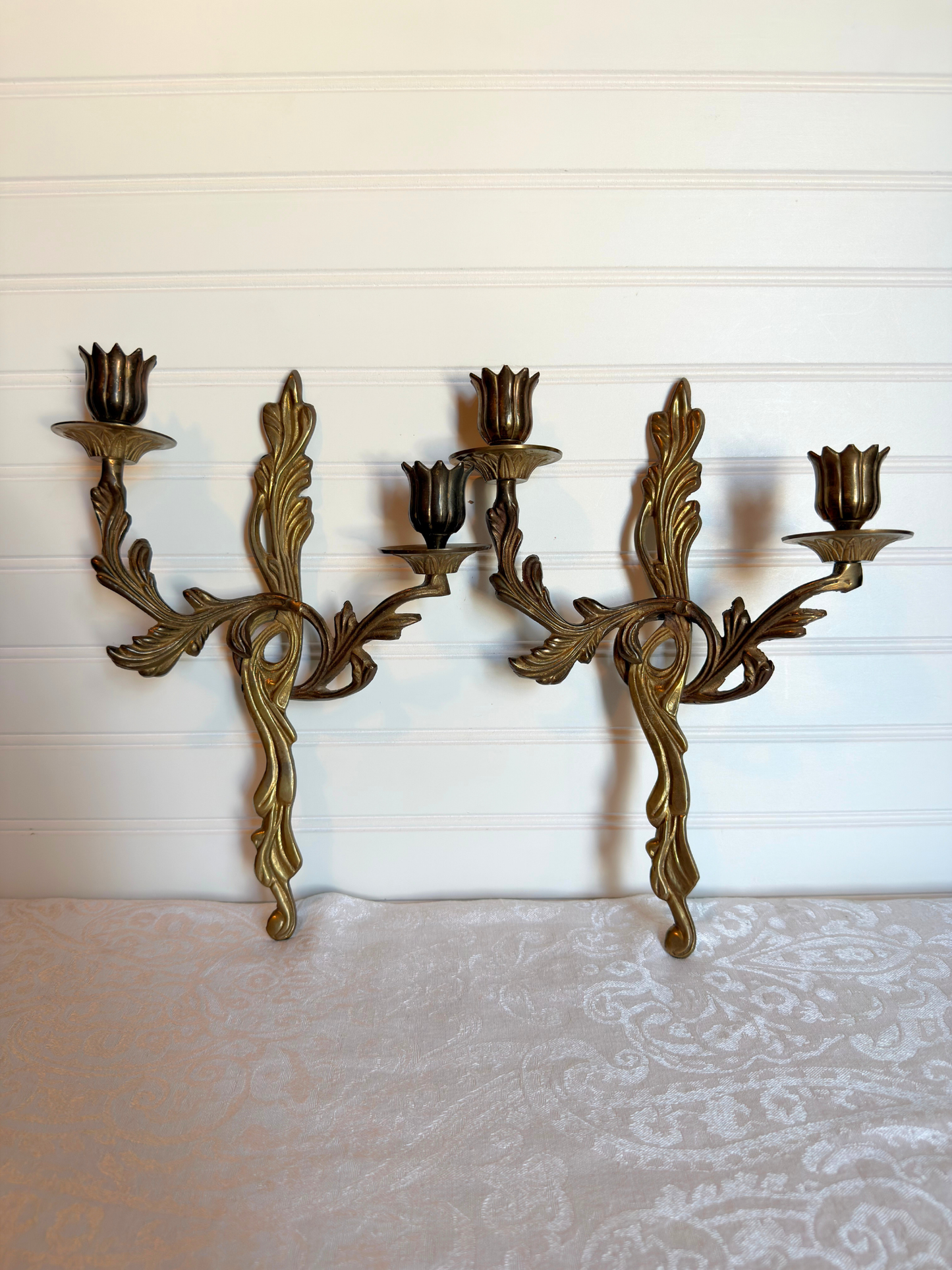 Pair of ornate brass wall sconces on a white background