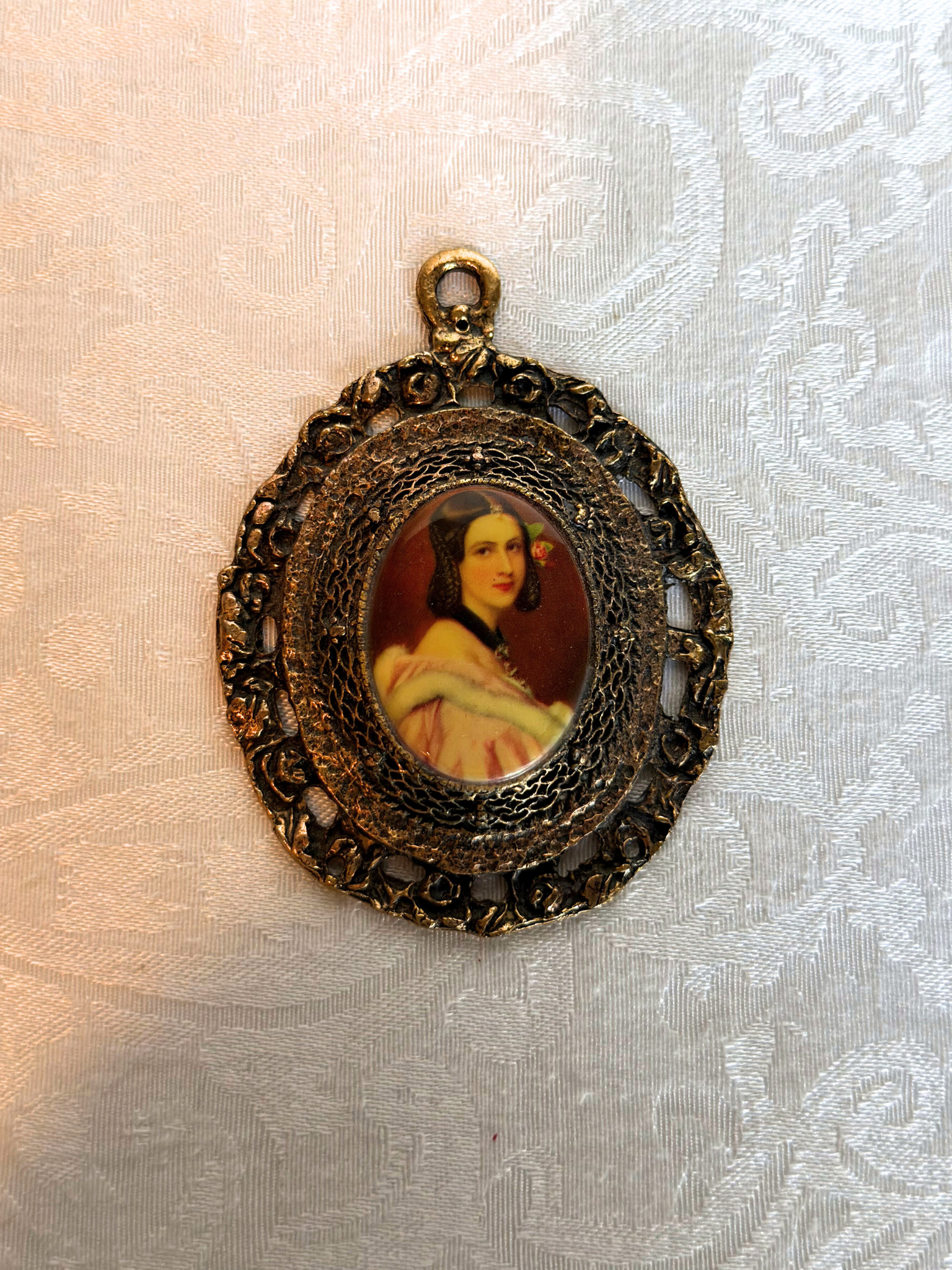 Decorative pendant with a portrait on a textured fabric background