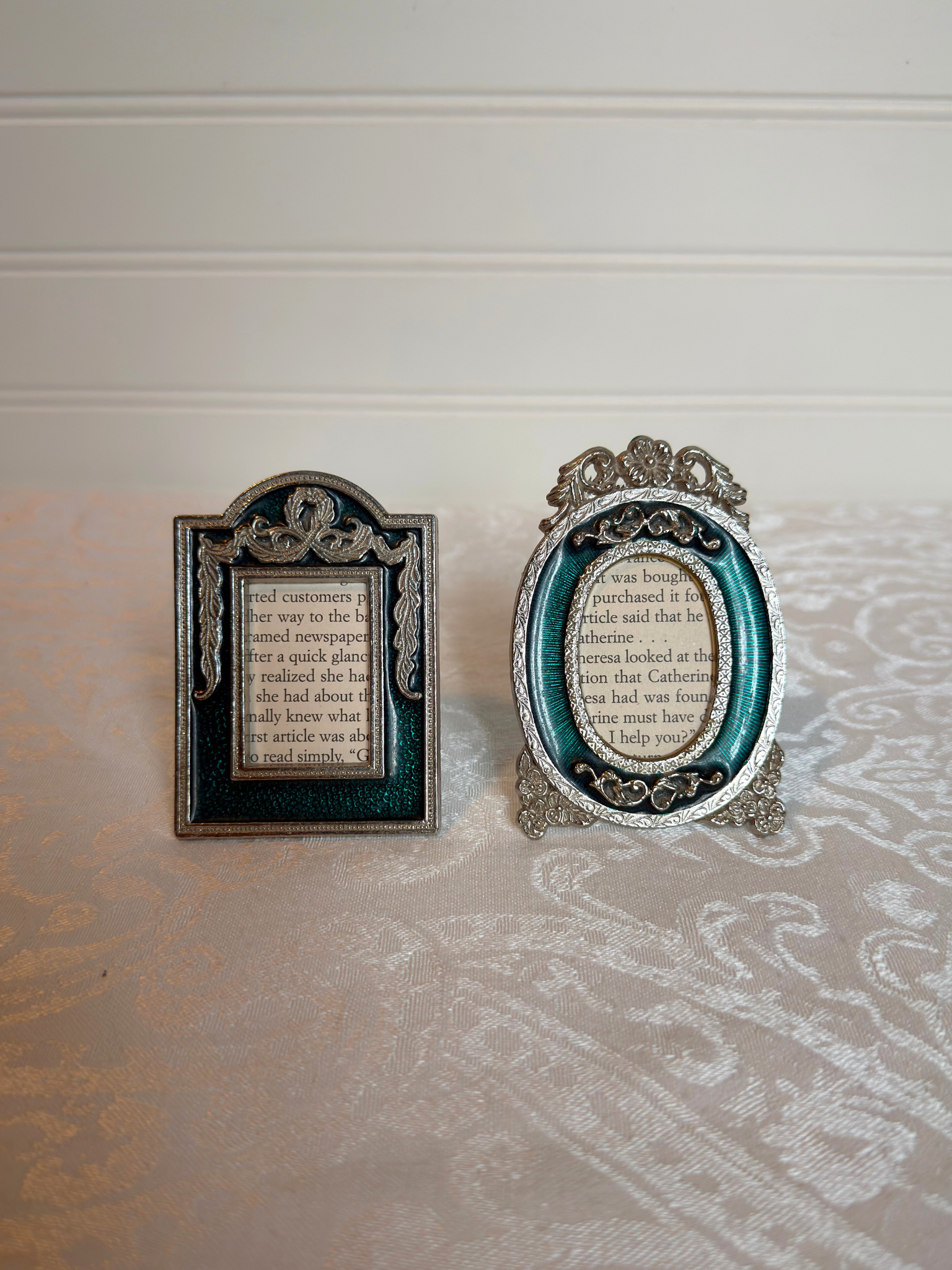 Two decorative teal and silver mini frames with text inside on a white background