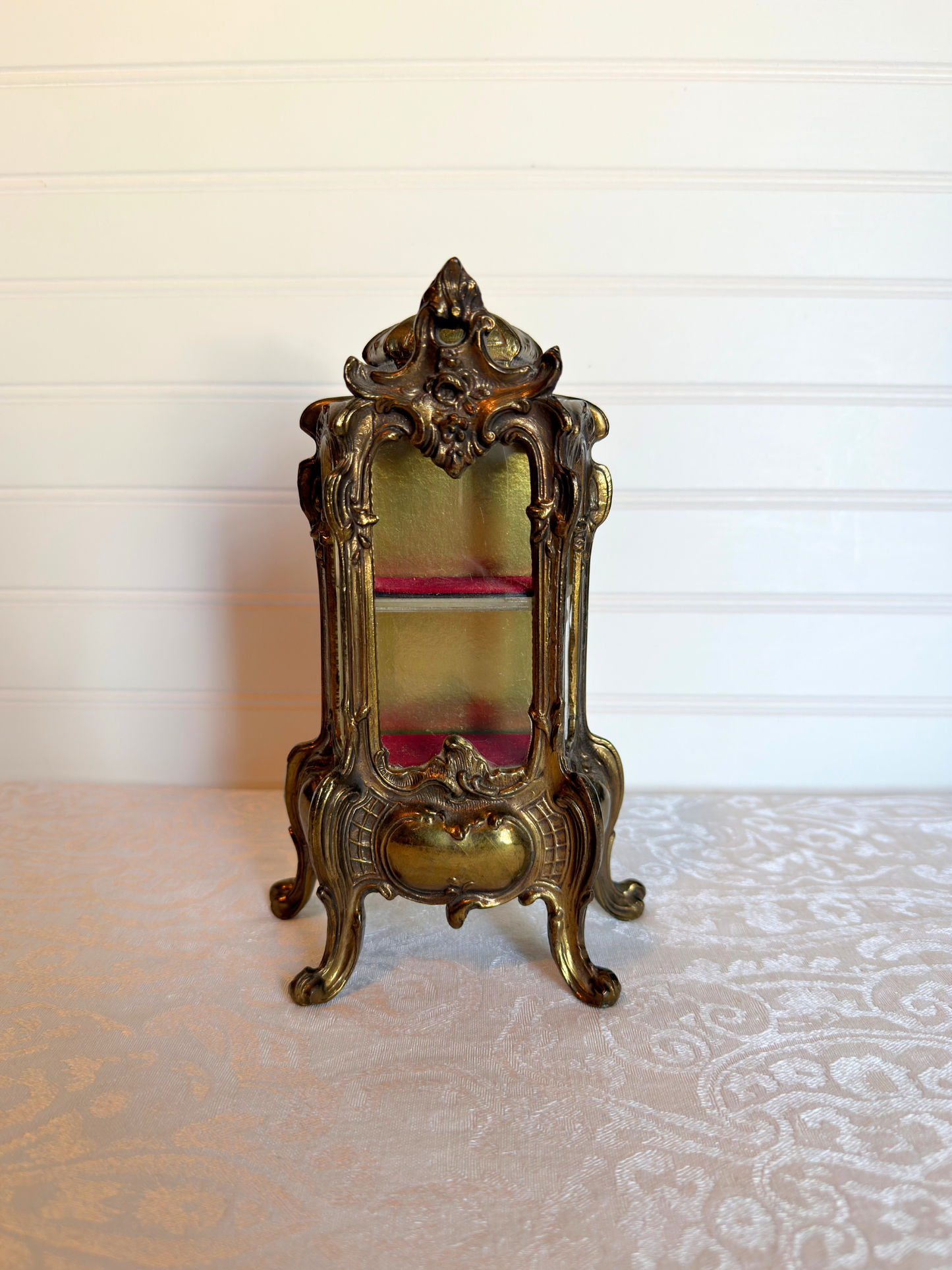 ornate vitrine jewelry box with red shelf on a white background