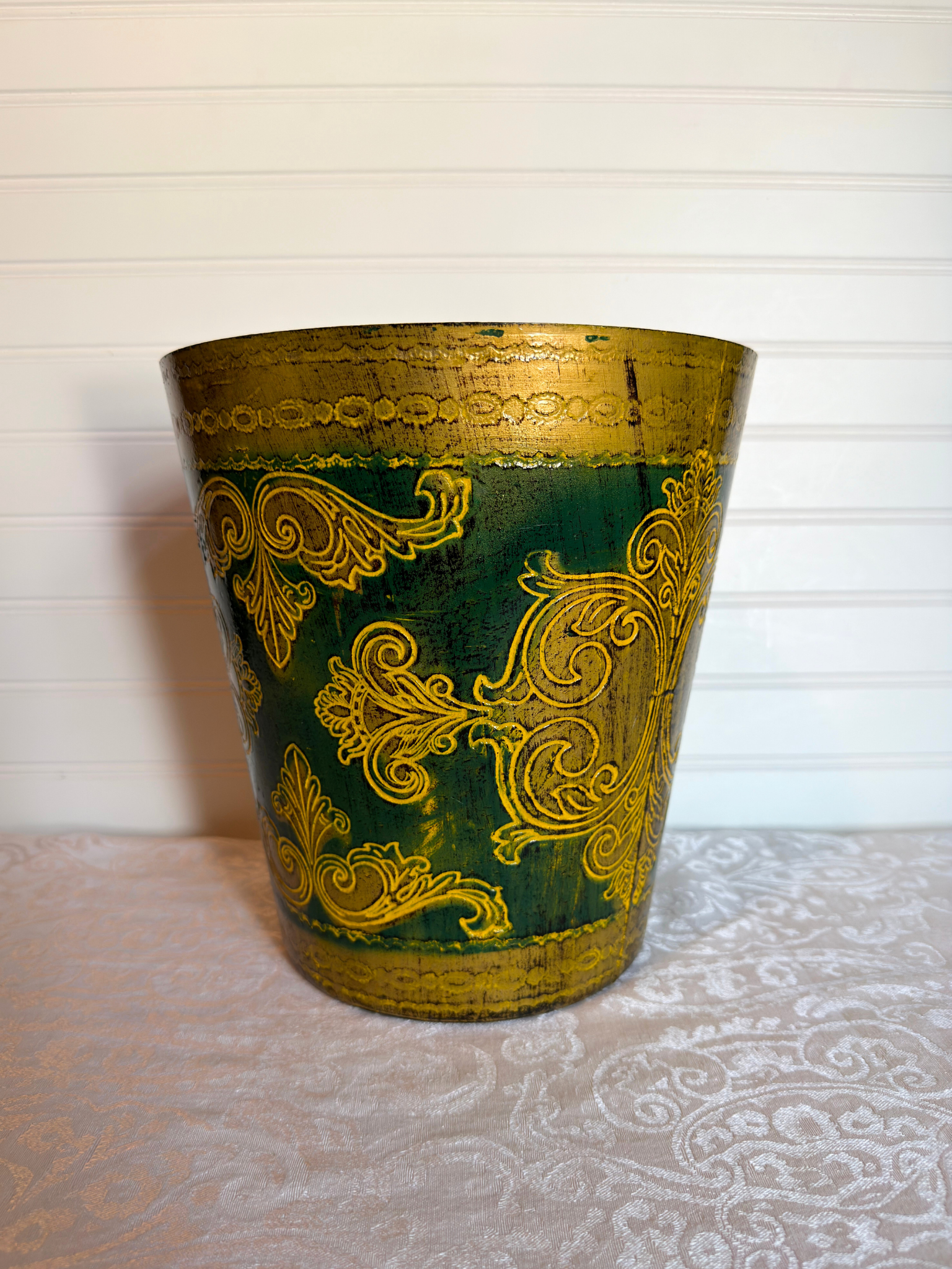 Decorative wastebasket with gold patterns on a green background