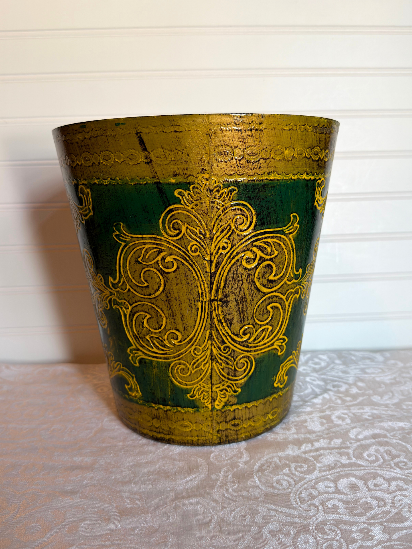 Decorative wastebasket with gold patterns on a green background
