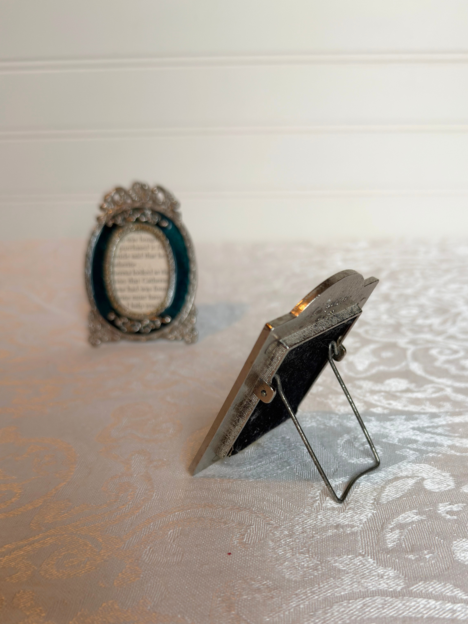 Two decorative teal and silver mini frames with text inside on a white background