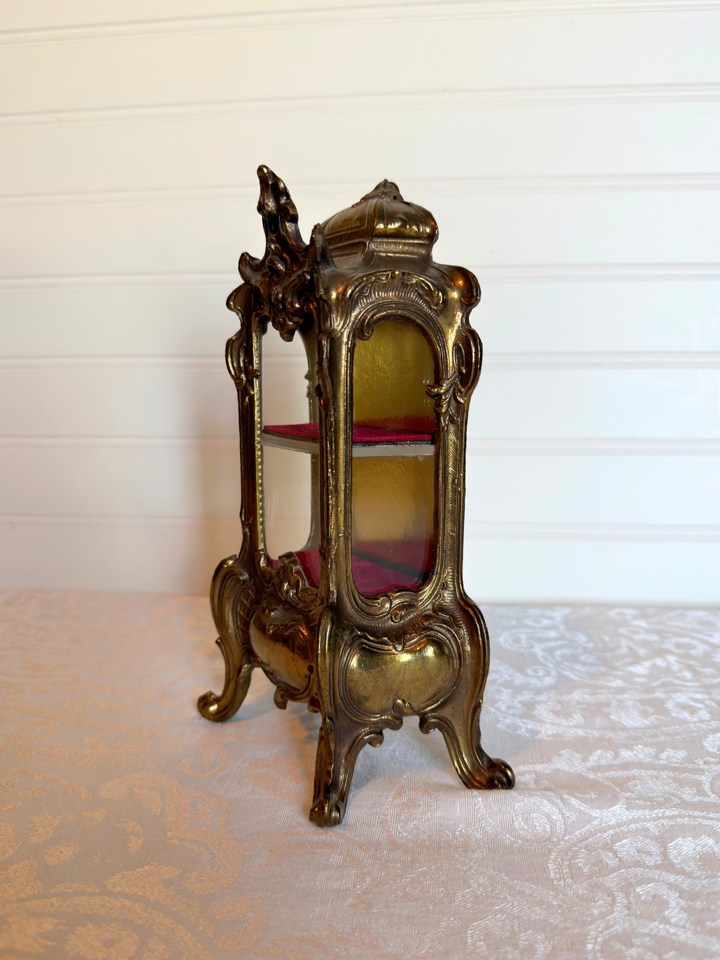 side of ornate vitrine jewelry box with red shelf on a white background